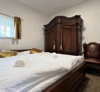 Schlafzimmer in der Villa mit Schrank, Sessel, Bett und goldenen Kissen.