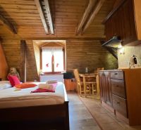 Holzbalken, Bett, Küchenzeile und Tisch im Dachgeschoss der Villa.