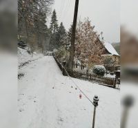 Eine verschneite Straße in Horné Otrokovce mit einem Einfamilienhaus und einem Zaun.