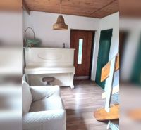 Innenraum eines Einfamilienhauses mit weißem Klavier, Holzboden, Treppe und Holzdecke.
