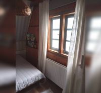 Ein Zimmer in einem Einfamilienhaus mit dunkler Holzverkleidung und einem Bett am Fenster.