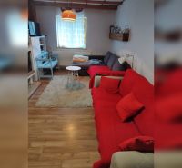 Wohnzimmer in einem Einfamilienhaus mit Holzboden und rotem Sofa.