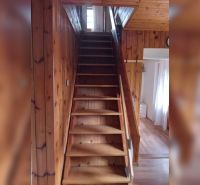Eine Holztreppe führt in einem Einfamilienhaus mit einem Boden in Holzoptik in den ersten Stock.