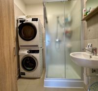 Badezimmer in einer 3-Zimmer-Wohnung mit Dusche, Waschmaschine und Trockner.