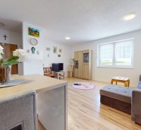 Wohnzimmer in einer 3-Zimmer-Wohnung mit Holzboden, Sofa und Blumen im Innenraum.