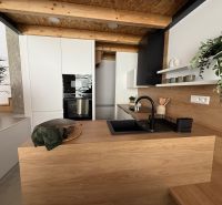 Moderne Küche in einem Einfamilienhaus mit Holzdekor und schwarzem Spülbecken.