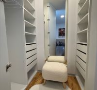 Ein Einfamilienhaus mit einem Kleiderschrank, einem Boden in Holzoptik und einem bequemen Stuhl.