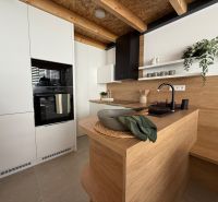 Küche in einem Einfamilienhaus mit Holzdekor, weißen Schränken und Pflanzen.