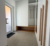 Eingangshalle in einem Einfamilienhaus mit Spiegel, Stauraum und hellen Fliesen.