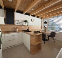Eine Küche in einem Einfamilienhaus mit Holzboden, Holzbalken und einem Esstisch.