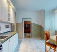 Küche in einer 3-Zimmer-Wohnung mit weißer Küchenzeile und Esstisch, Boden mit Dekor.