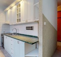 Küche in einer 3-Zimmer-Wohnung mit weißen Schränken und grüner Arbeitsplatte.