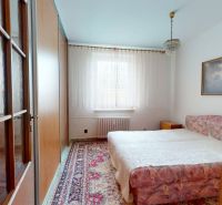 Schlafzimmer in einer 3-Zimmer-Wohnung mit Teppichdekor und Bild an der Wand.