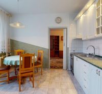 Küche in einer 3-Zimmer-Wohnung mit Esstisch, weißen Schränken und grüner Arbeitsplatte.