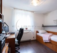 Ein Zimmer in einem Einfamilienhaus mit einem Bett, einem Schreibtisch und einem Boden mit Holzdekor.