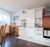 Küche in einem Einfamilienhaus mit weißen Schränken und einem Boden in Holzoptik.