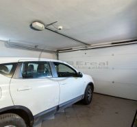 Ein Auto, das in der Garage eines Einfamilienhauses mit weißen Wänden und Fliesenboden geparkt ist.