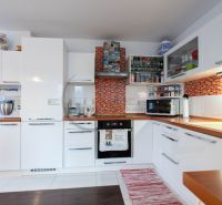 Küche in einem Einfamilienhaus mit weißen Schränken und einem Boden in Holzoptik.