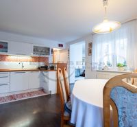 Eine Küche in einem Einfamilienhaus mit weißen Schränken, orangefarbenen Fliesen und einem Boden in Holzoptik.