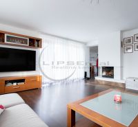Wohnzimmer in einem Einfamilienhaus mit Kamin, Fernseher und Holzboden.