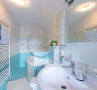 Ein Badezimmer in einem Einfamilienhaus mit einem weißen Waschbecken, einer Badewanne, einem Spiegel und einem Handtuchhalter.