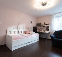 Kinderzimmer mit weißem Bett, Schreibtisch, Stuhl und Boden in Holzoptik.