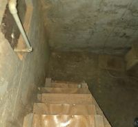 Eine Treppe, die in den Keller führt, mit Wänden, an denen sichtbare Rohre in den Gärten sind.