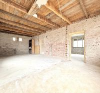 Innenraum eines Einfamilienhauses mit freiliegenden Ziegeln und Holzbalkendecke.
