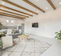 Wohnzimmer in einem Einfamilienhaus mit Balkendecke, Sofa und Pflanzen, Boden mit Holzdekor.
