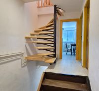 Interieur einer Maisonette-Wohnung mit Holztreppe und Eingang zu einem Raum.
