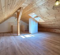 Ein Dachzimmer mit Holzverkleidung und einem Boden in Holzoptik.