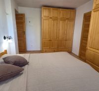 Schlafzimmer in einer 2-Zimmer-Wohnung mit Holzschränken, Bett und Boden mit Holzdekor.