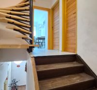 Eine Treppe mit einem hölzernen Geländer führt zu einer 2-Zimmer-Wohnung mit Blick auf die Eingangstür.