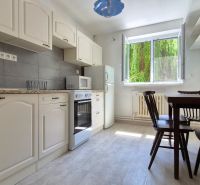 Küche mit weißen Schränken und Esstisch in einer 2-Zimmer-Wohnung.