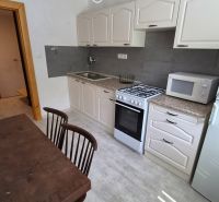Küche in einer 2-Zimmer-Wohnung mit Holztisch, Mikrowelle und Gasherd.