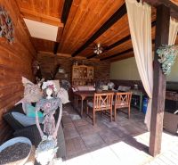 Überdachte Sitzecke mit Holzverkleidung in einem Einfamilienhaus, dekoriert mit einer Skulptur und Vorhängen.