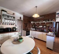 Eine Küche in einem Einfamilienhaus mit Ziegelverkleidung und einem Boden in Holzoptik.