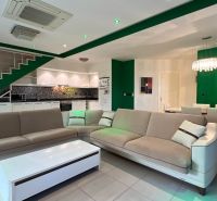 Ferienwohnung mit geräumigem Sofa, weißen Küchenschränken und einer Leuchte über dem Essbereich.