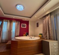 Ferienwohnung mit Whirlpool, Holzboden, rosa Wände, Fernseher, Vorhänge.