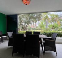 Im Ferienapartment gibt es Rattanmöbel mit Blick auf den Garten.