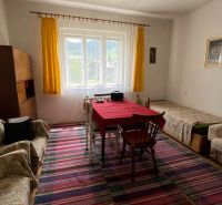 Ein Zimmer in einem Einfamilienhaus mit einem bunten Teppich und einem roten Tischtuch auf dem Tisch.