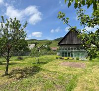 Ein Einfamilienhaus in Liptovská Lúžna mit Obstbäumen und einem Gewächshaus im Garten.