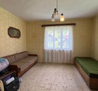 Ein Zimmer in einem Einfamilienhaus mit Sofas, gemusterten Tapeten und einem Holzboden.