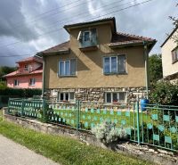 Ein Einfamilienhaus in Kalameny, mit einem Steinfundament und einem bunten Zaun.