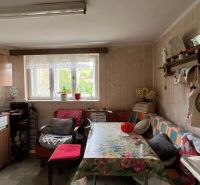 Eine Küche in einem Einfamilienhaus mit einem Blumen-Tischtuch und einfacher Einrichtung.