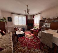 Wohnzimmer in einem Einfamilienhaus mit Blumen, Teppich und bequemen Sitzgelegenheiten.