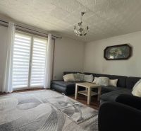 Wohnzimmer in einer 3-Zimmer-Wohnung mit großem Sofa, Holzboden und Dekorationen.
