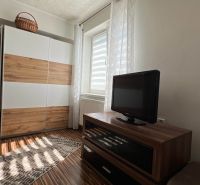 Ein Zimmer in einer 3-Zimmer-Wohnung mit einer Kommode, einem Fernseher und einem Boden mit Holzdekor.