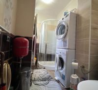 Badezimmer in einer 3-Zimmer-Wohnung mit Waschmaschine, Duschkabine und Installationen.