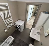Badezimmer in einer Einzimmerwohnung mit Waschmaschine, Waschbecken und Toilette.